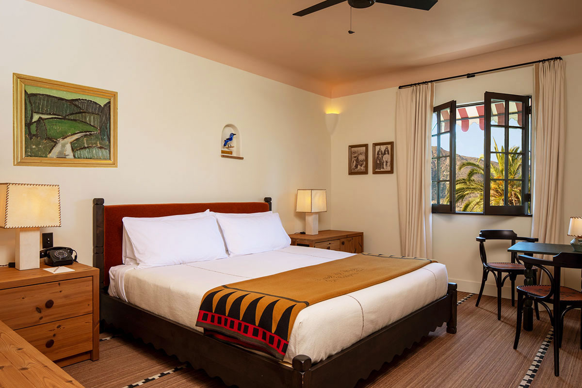King Room bed with windows onto greenery at Hotel El Roblar