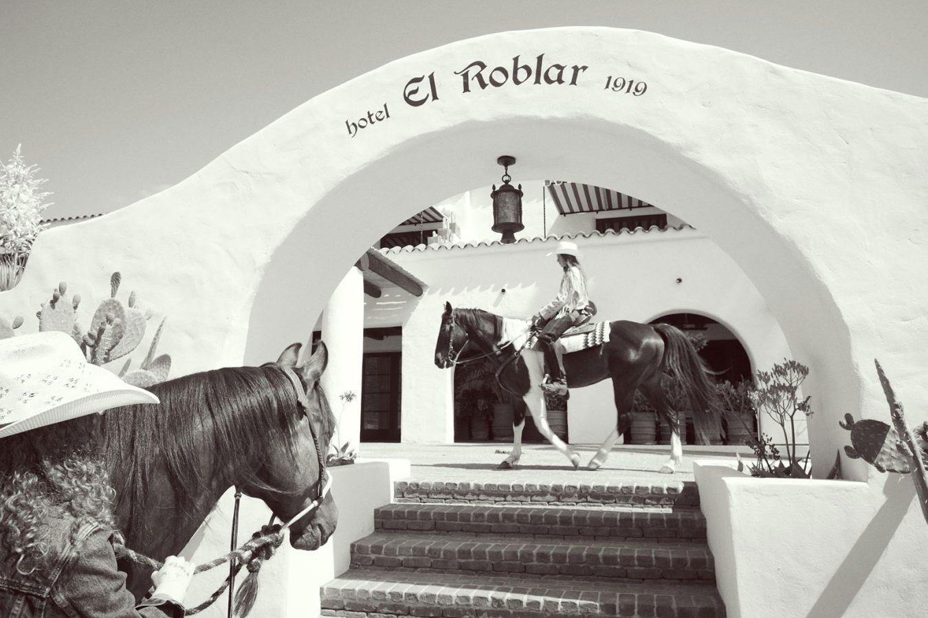 Woman on a horse in front of black and white facade image of Hotel El Roblar