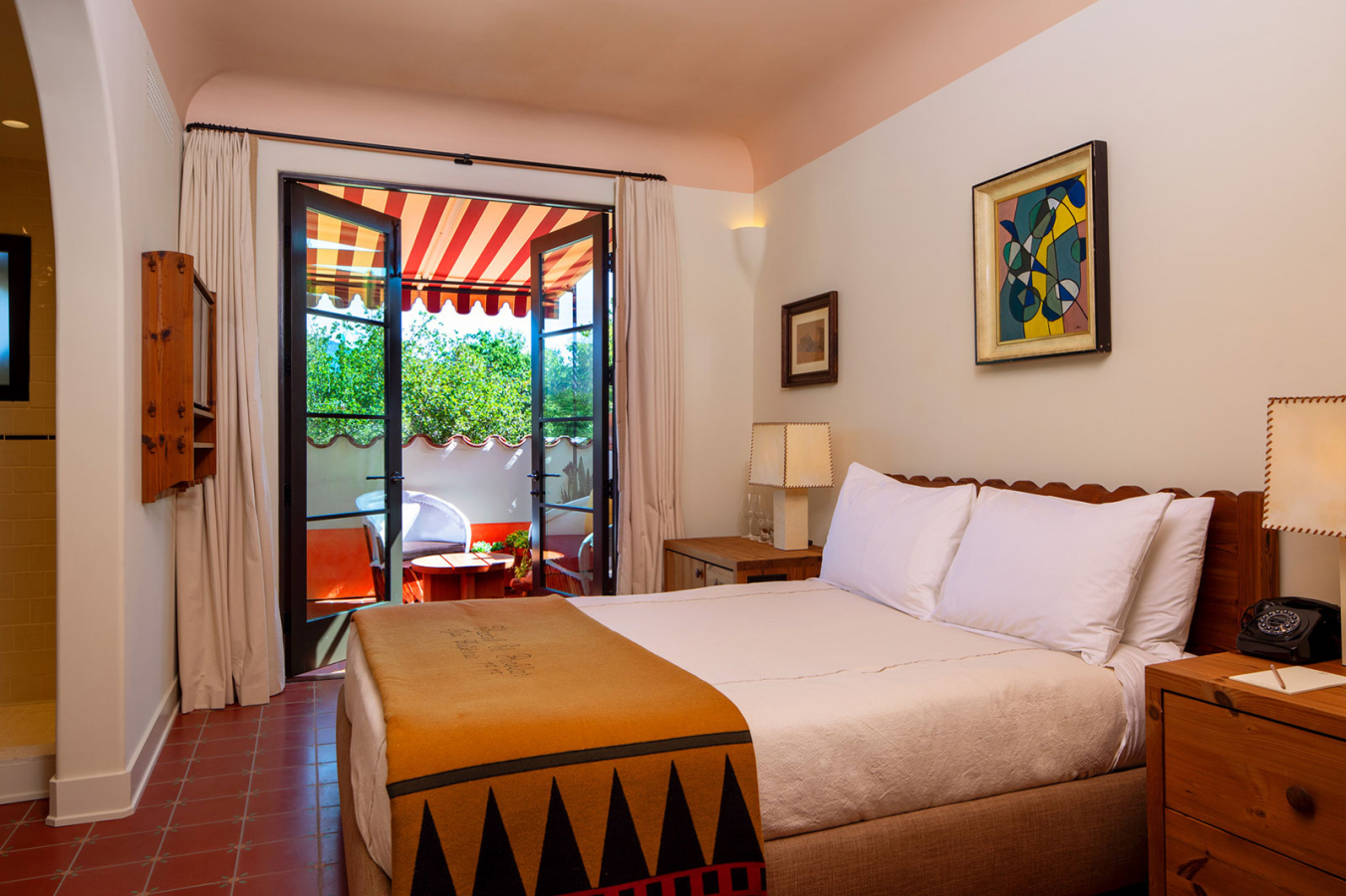 Large bed with open doors to the terrace in the Queen with Terrace room at Hotel El Roblar