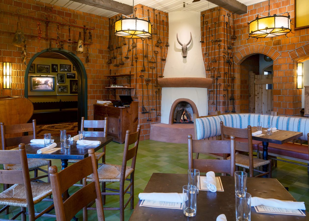 Main indoor dining area with large fireplace and green tile floor at Hotel El Roblar's La Cocina